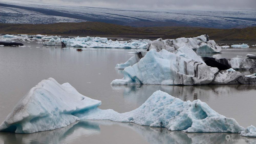 A zodiac in the distance among the icebergs.