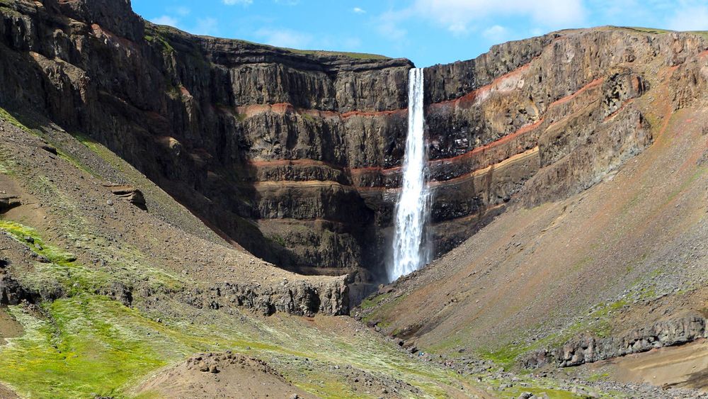 Hengifoss se situe au fond, dans son étonnant décor strié de rouge.