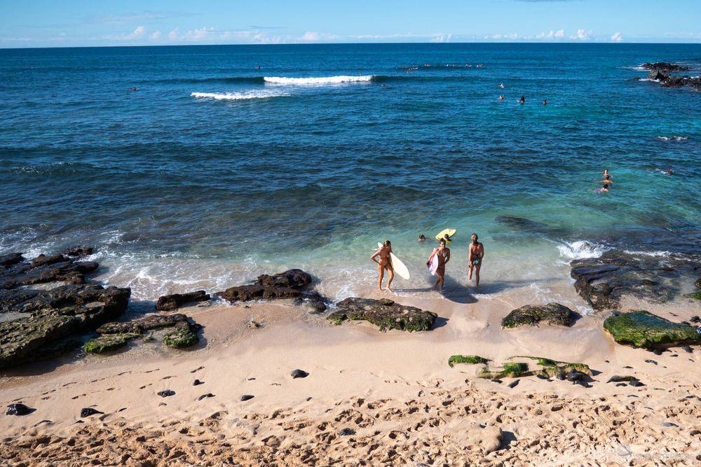Surfeurs et baigneurs à marée basse.