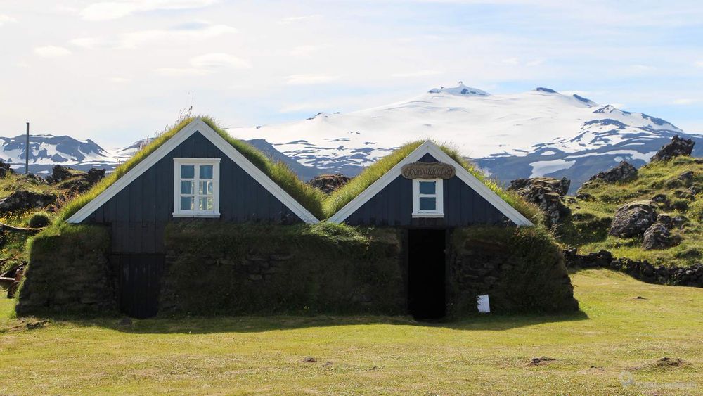 Petites maisons au toit de tourbe au musée maritime d'Hellissandur avec le Snæfellsjökull en arrière plan.