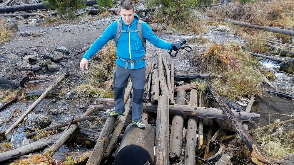 Flo traverse le pont sur les troncs d'arbres.